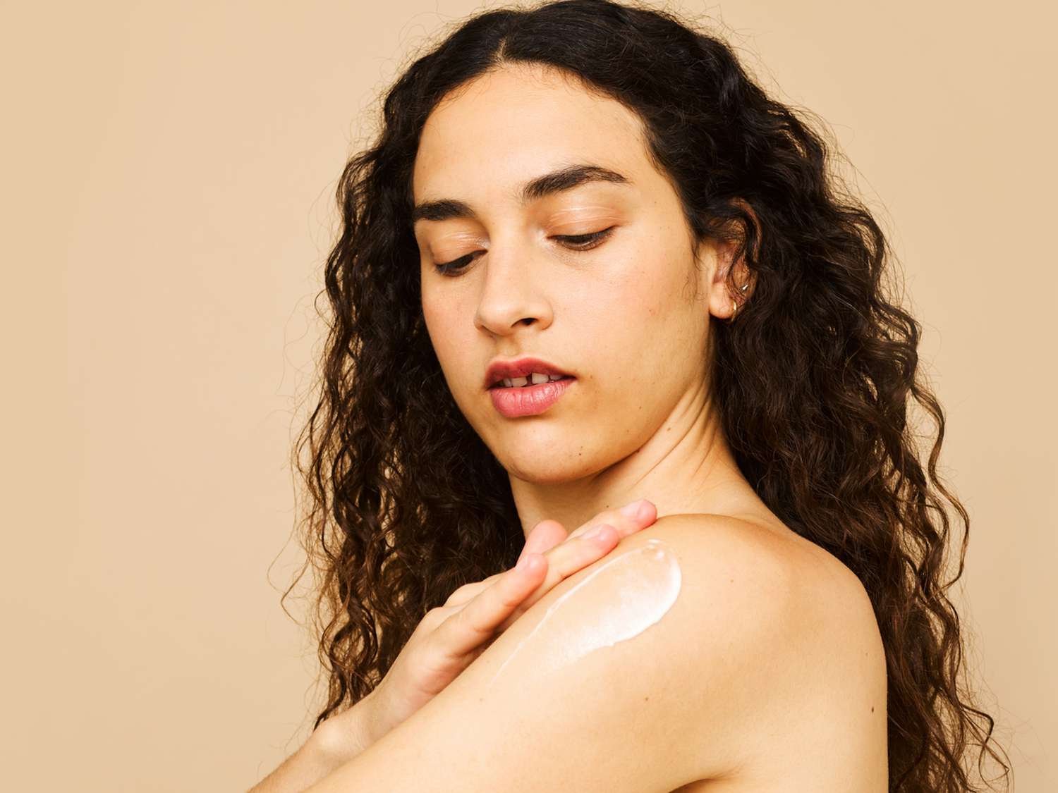 woman applying lotion to shoulder 